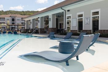 a pool with blue lounge chairs in front of a building