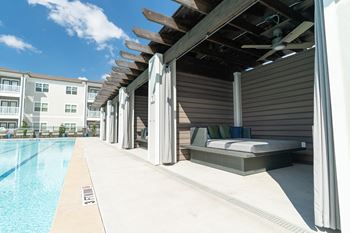 Sundeck with lounge chairs, tables with chairs, and four cabanas
