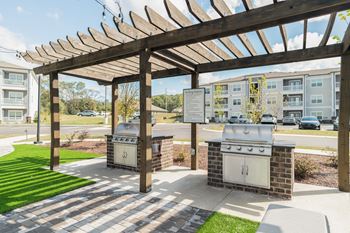 Outdoor beer garden styled with decorative lighting, private seating, fire pit, corn hole, and covered grilling stations