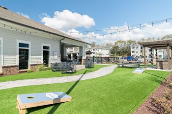 Outdoor beer garden styled with decorative lighting, private seating, fire pit, corn hole, and covered grilling stations