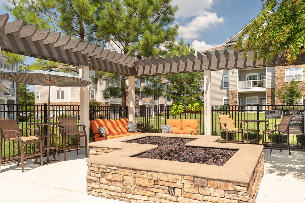 a clubhouse patio with a fire pit and seating area with chairs and umbrellas