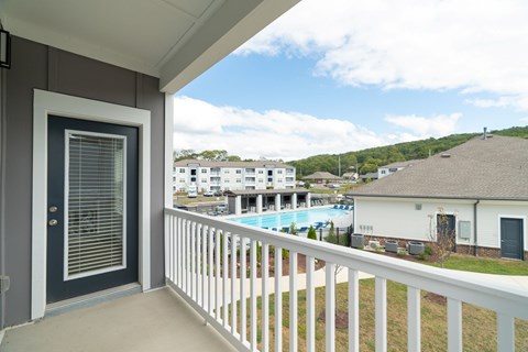 A balcony with a view of a pool and houses.