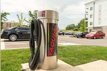 A Vacudry vacuum cleaner is on a grassy area in front of a parking lot.