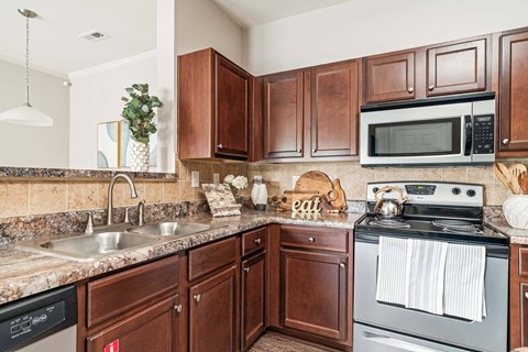 A kitchen with brown cabinets and a black dishwasher.