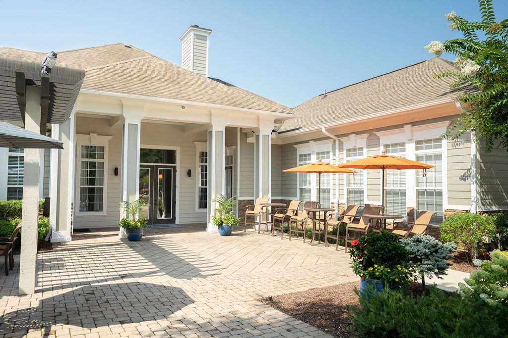 a patio with chairs and umbrellas in front of a house