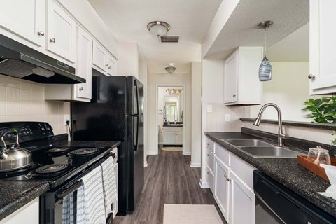 A kitchen with black appliances and white cabinets.