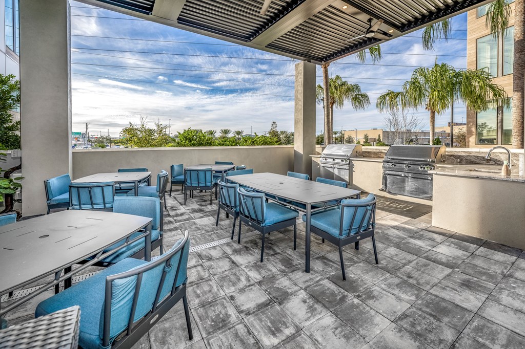 a patio with tables and chairs and a grill