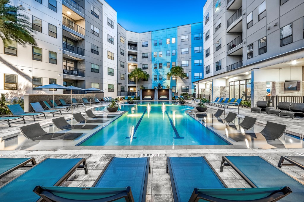 an apartment swimming pool with lounge chairs in front of an apartment building