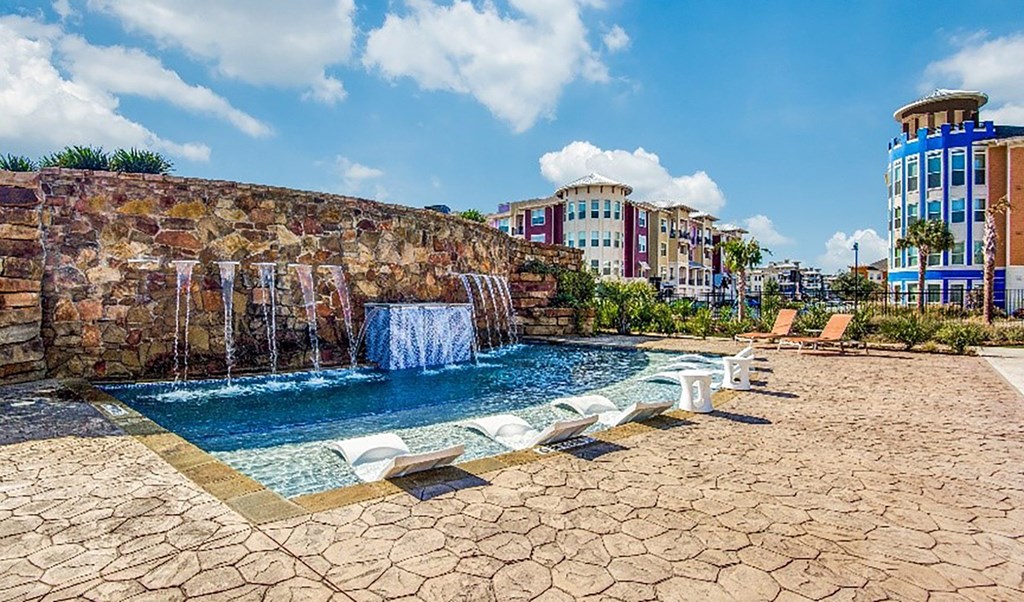 a swimming pool with a waterfall and buildings in the background