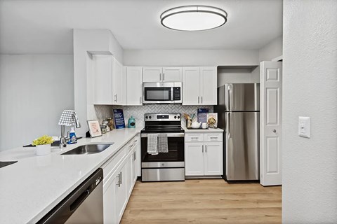 A modern kitchen with white cabinets and stainless steel appliances.