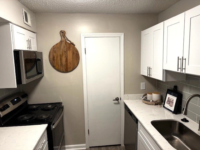 A kitchen with white cabinets and a wooden cutting board hanging on the wall.