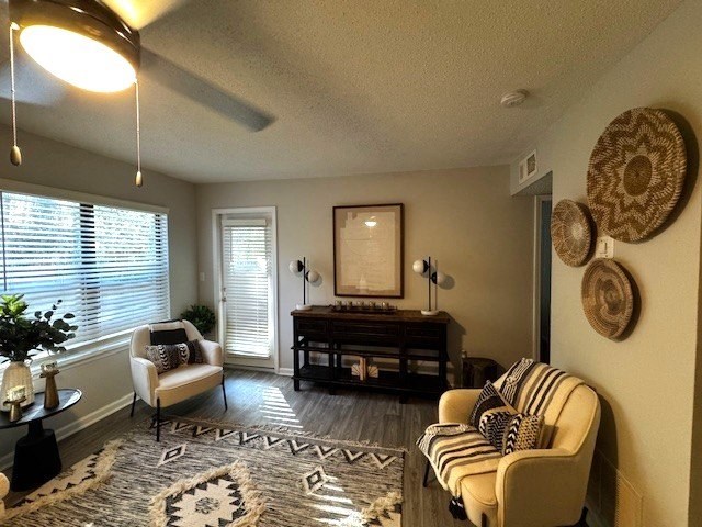 A living room with a rug, a chair, a sofa, a table, and a picture frame on the wall.