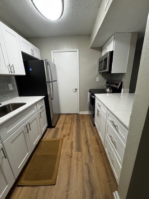 A kitchen with white cabinets and a black fridge.