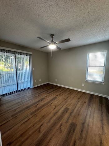 A room with a ceiling fan and sliding glass doors.