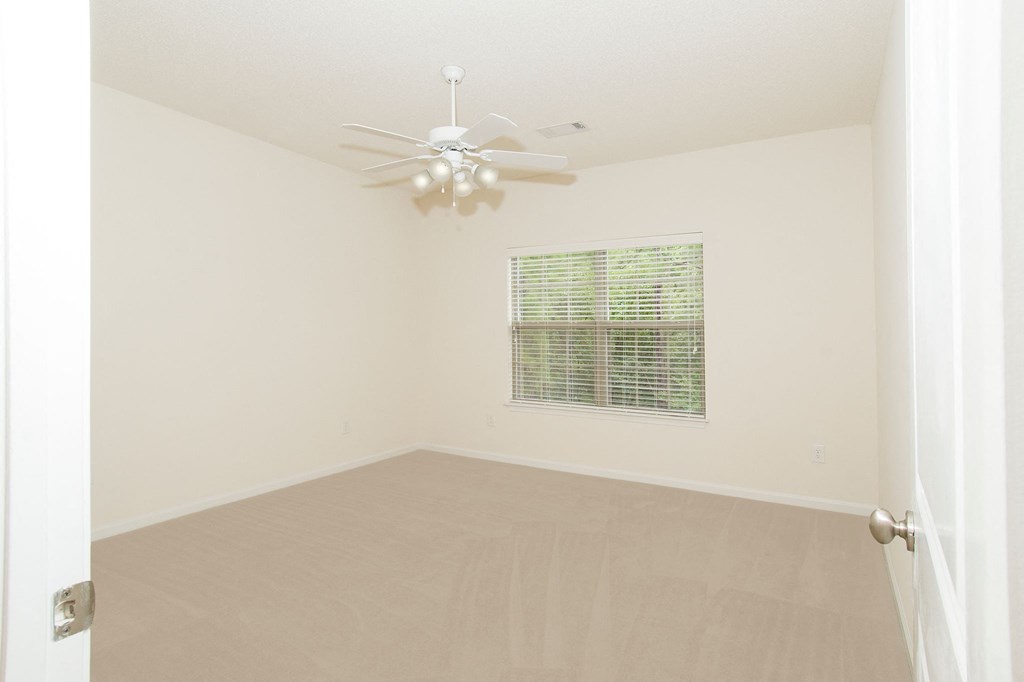 an empty living room with a ceiling fan and a window