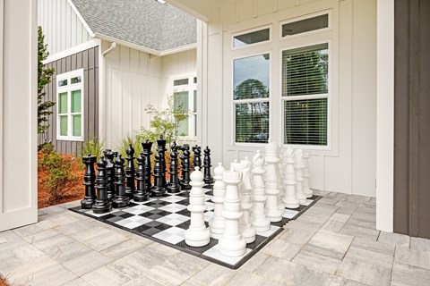 A giant chess set is set up on a patio.
