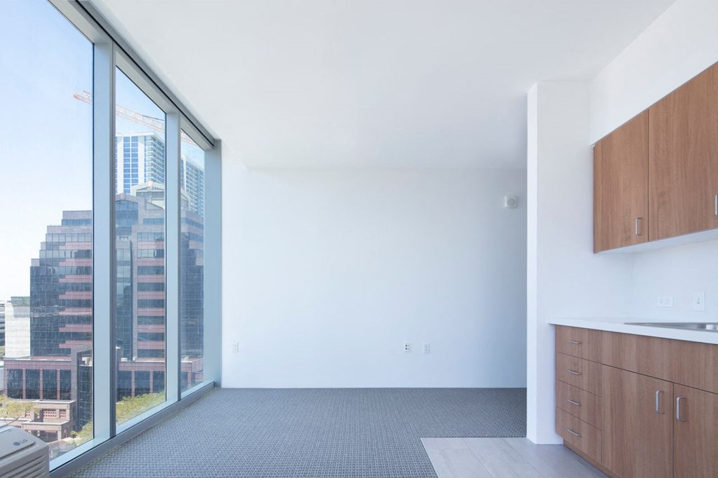 an empty room with a large window and a kitchen