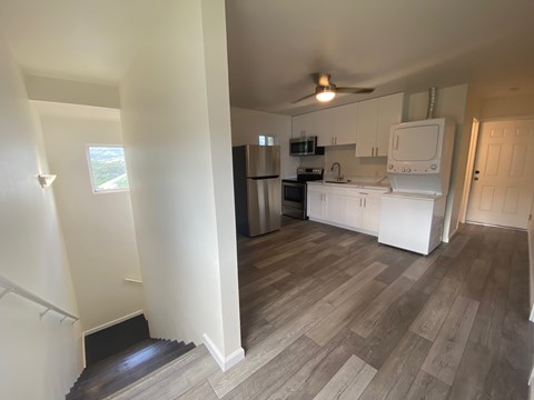 A kitchen with white cabinets and a wooden floor.