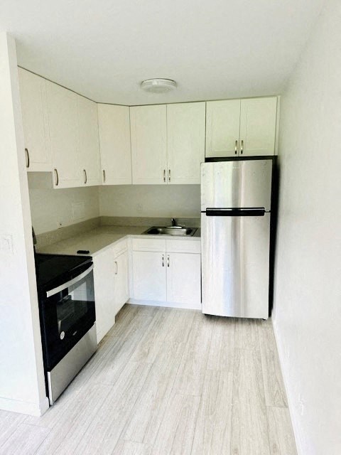 A kitchen with white cabinets and a stainless steel refrigerator.