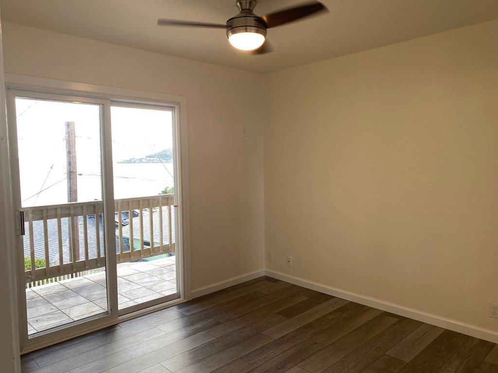 an empty living room with a balcony and a ceiling fan