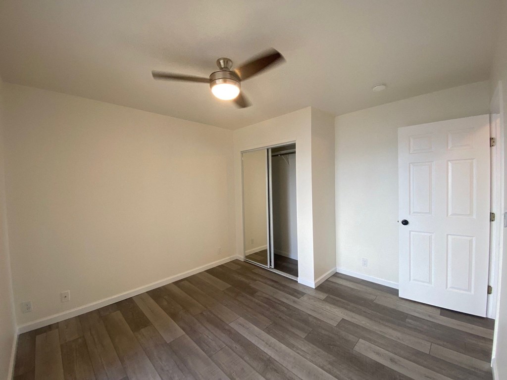 an empty living room with a ceiling fan and a closet