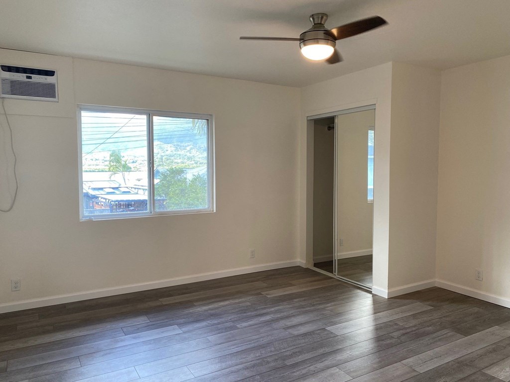 an empty living room with a window and a ceiling fan
