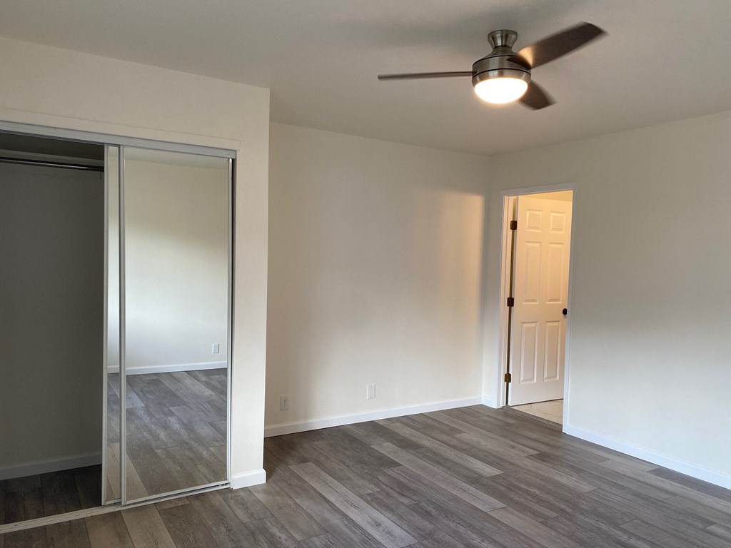 an empty living room with a ceiling fan and a mirror