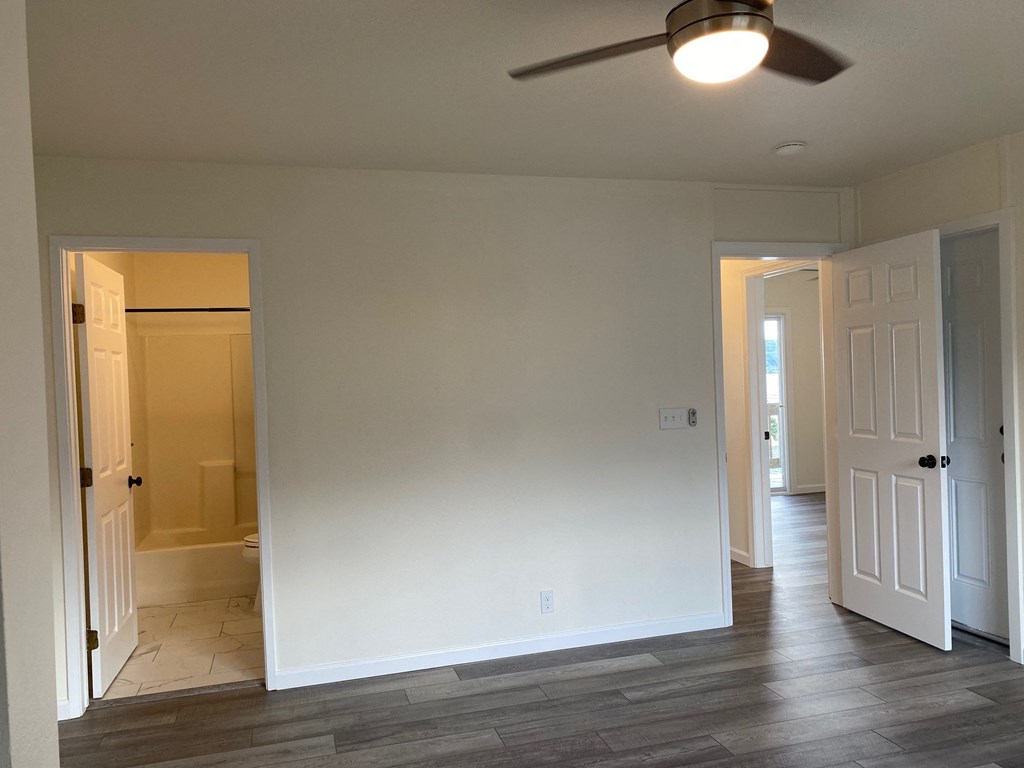 a living room with white walls and a ceiling fan