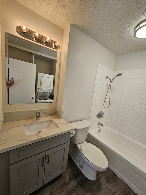 a bathroom with gray cabinets and a white bathtub