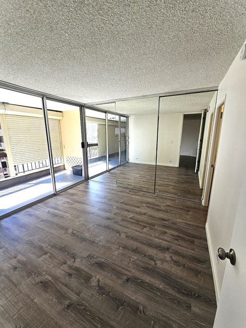 an empty living room with hardwood floors and a balcony