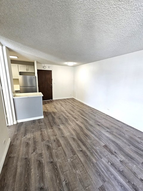 an empty living room with a kitchen in the background