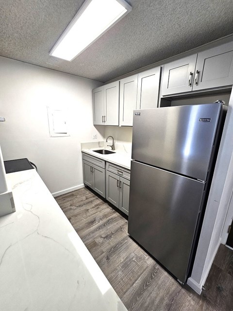 A kitchen with a stainless steel refrigerator and white countertops.