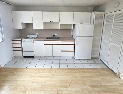 A kitchen with white appliances and wooden floors.