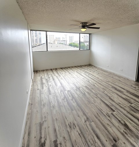 an empty living room with wood flooring and a window