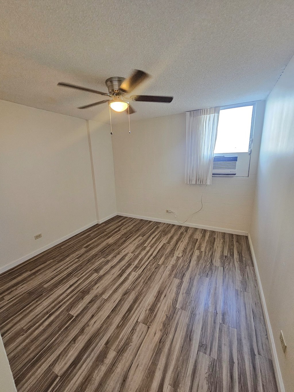 an empty living room with wood flooring and a ceiling fan