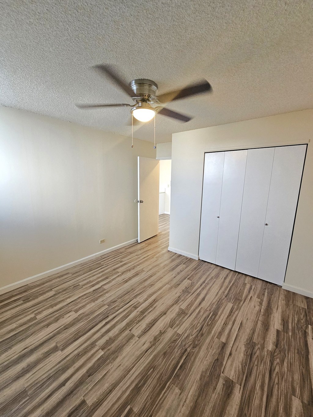 an empty living room with a ceiling fan and a closet