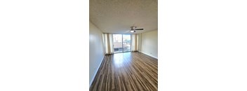 an empty living room with wood flooring and a ceiling fan