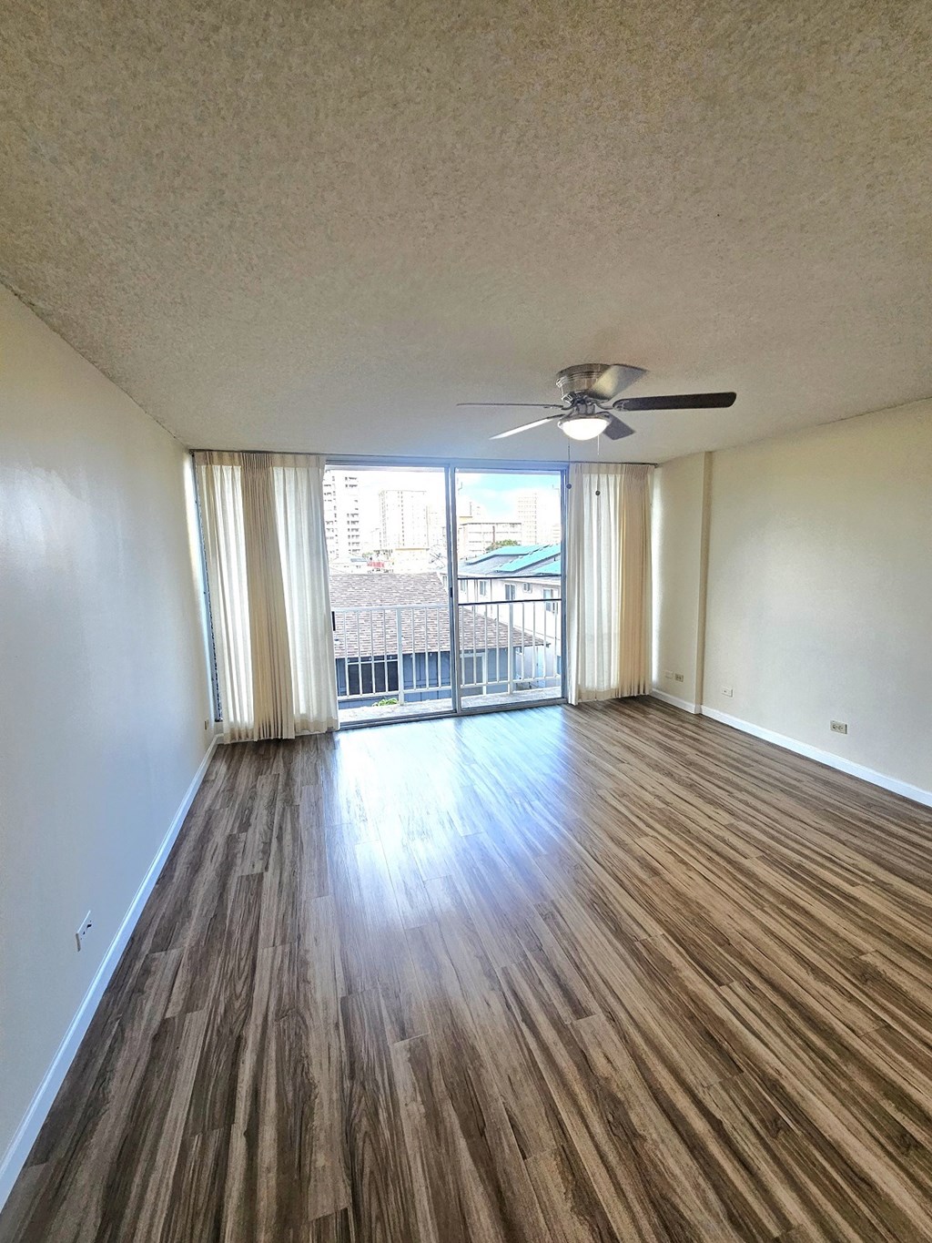 an empty living room with wood flooring and a ceiling fan