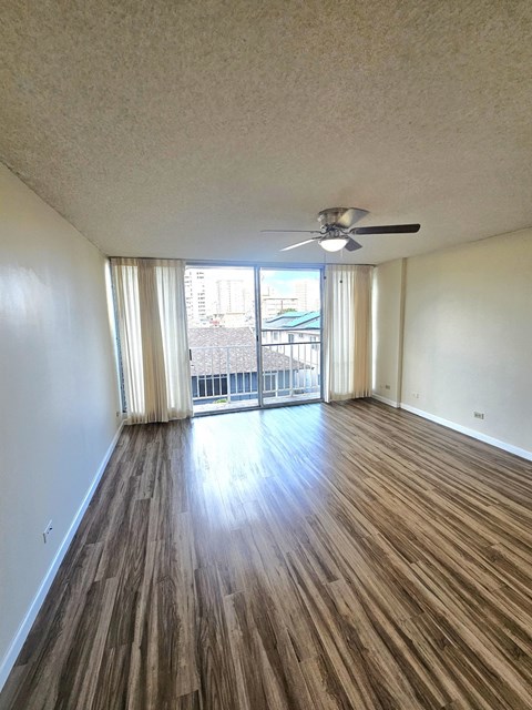 an empty living room with wood flooring and a ceiling fan