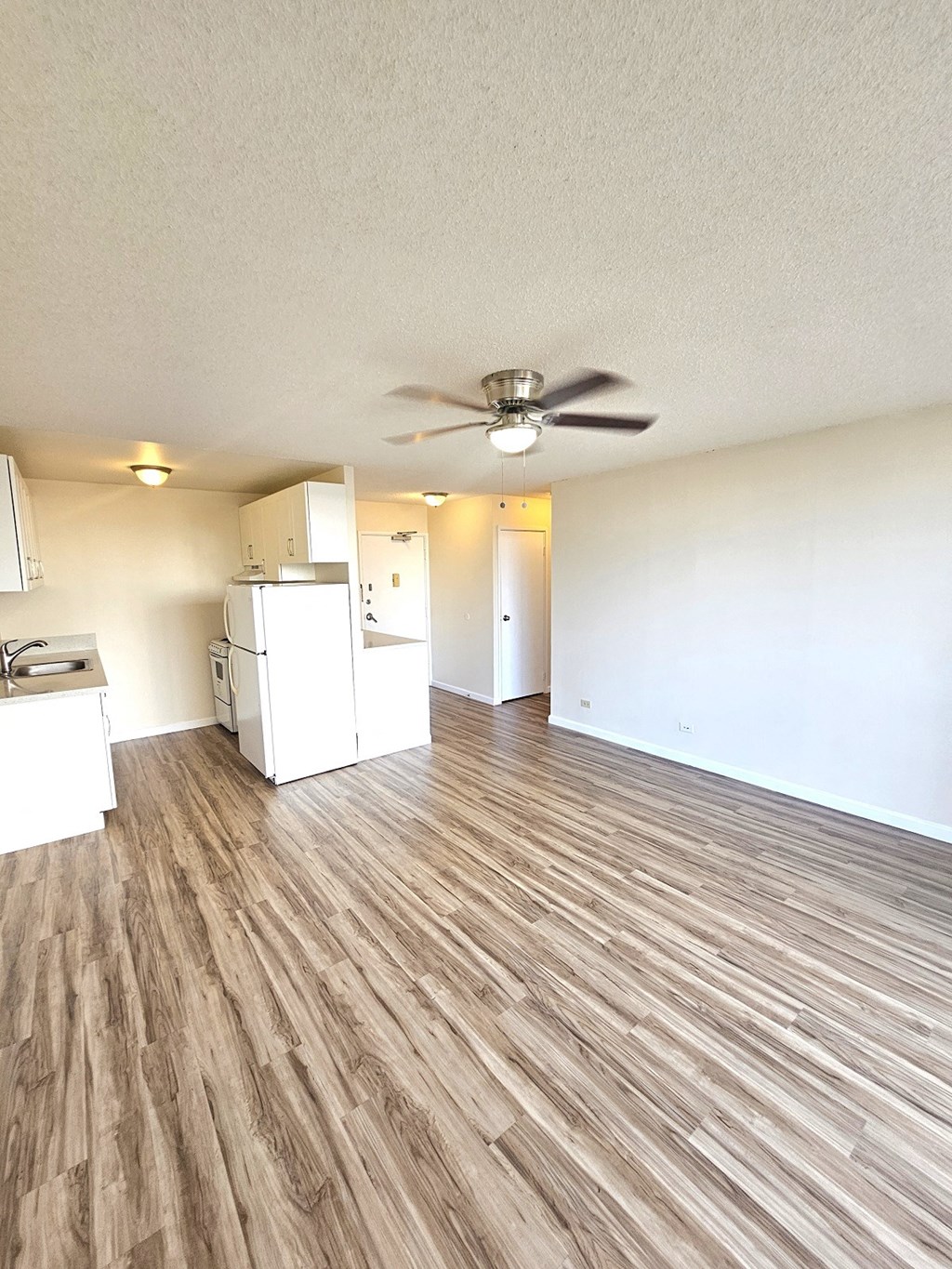 an empty living room and kitchen with a ceiling fan
