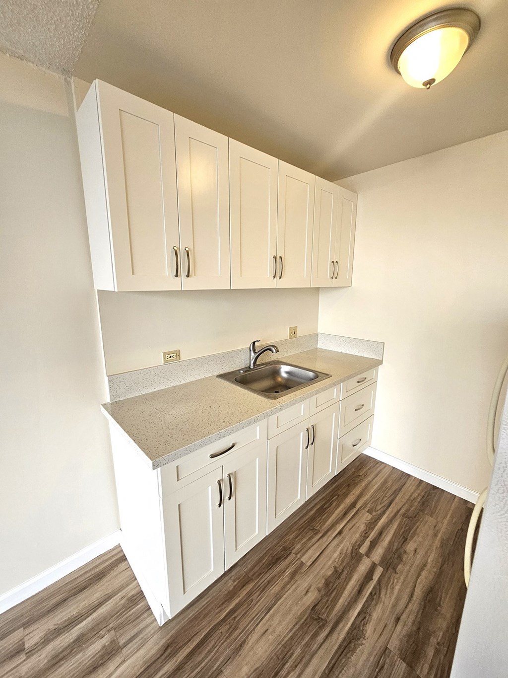 an empty kitchen with white cabinets and a sink
