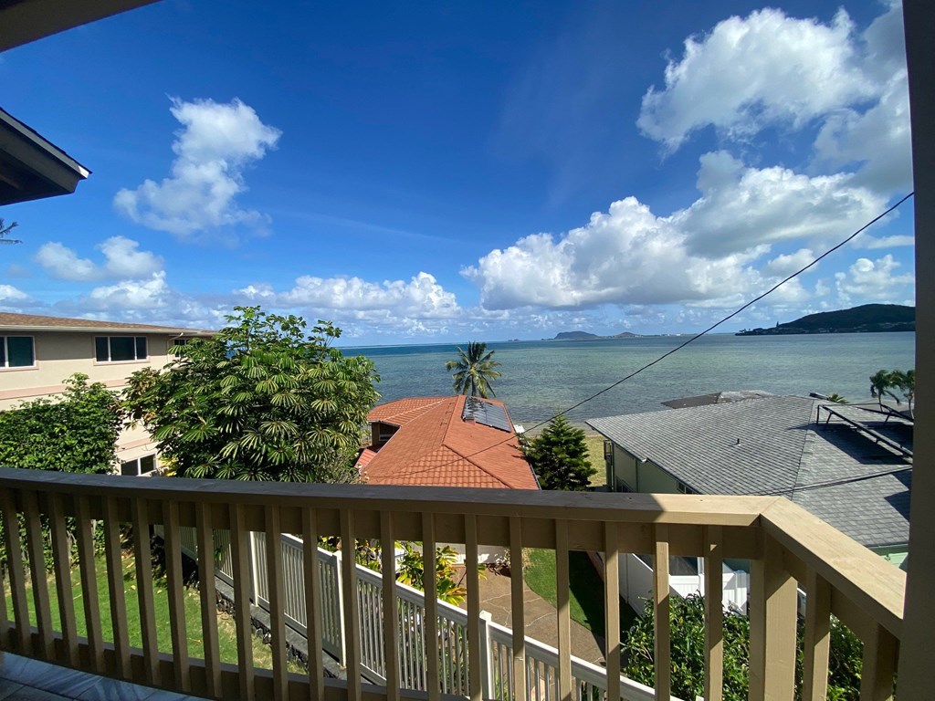 a view of the ocean from the balcony of a house with a deck