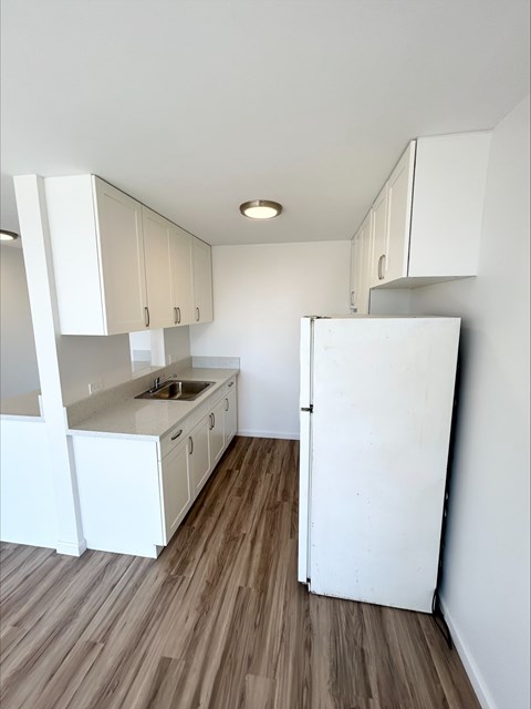 A kitchen with white cabinets and a white fridge.