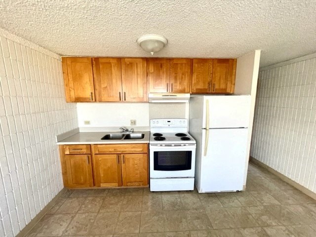 a kitchen with a white refrigerator freezer and a stove top oven