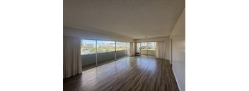 A room with wooden floors and a view of the city through large windows.