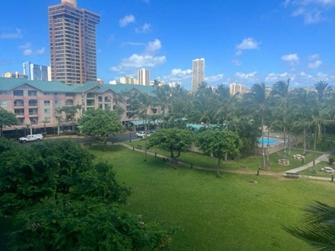 A view of a resort with a swimming pool and tall buildings in the background.