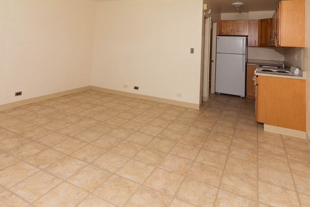 an empty room with a kitchen and a refrigerator