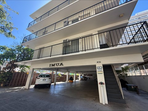 A white car is parked in the garage of a multi-story building.