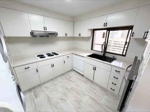 A kitchen with white cabinets and a tiled floor.
