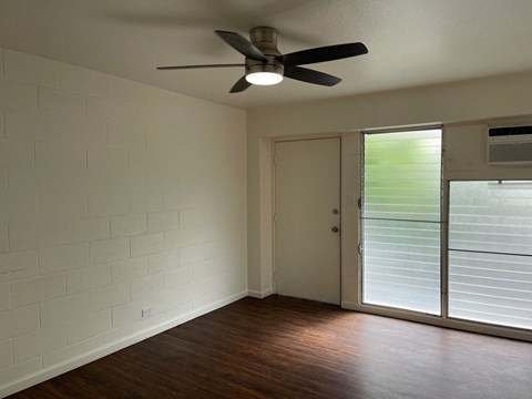 A room with a ceiling fan and sliding glass doors.